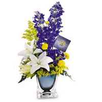 This bouquet in a smoked blue-gray square cut glass vase is appropriate for female and male bosses. The bouquet features a white lily, blue delphinium, yellow button pompons and more. Approx. 18H x 8W 